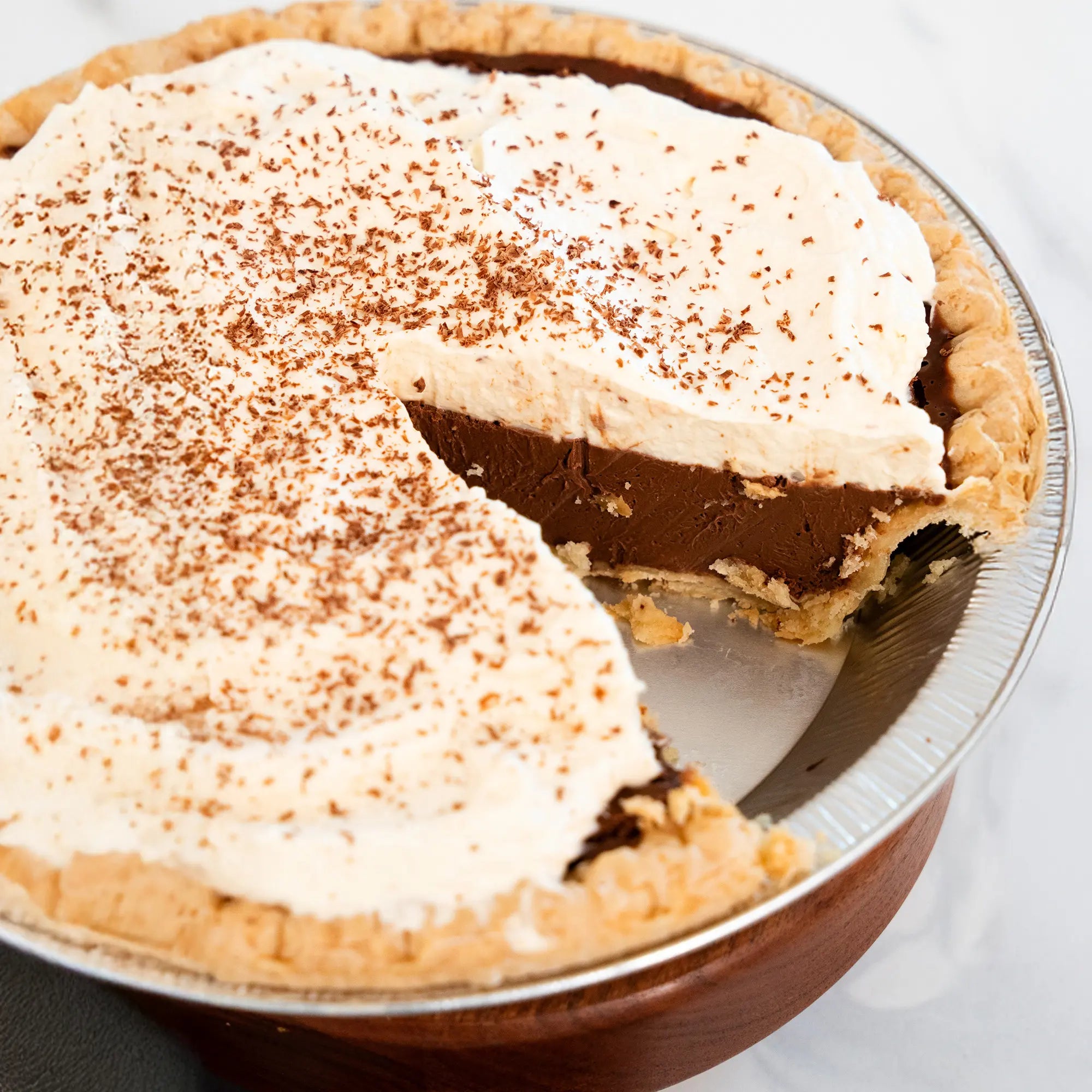 Angeschnittene Schokoladen-Pot-de-Crème-Tarte mit dicker Sahnehaube und Schokoraspeln